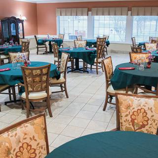 A spacious dining area with multiple tables and chairs, decorated in a classic style.