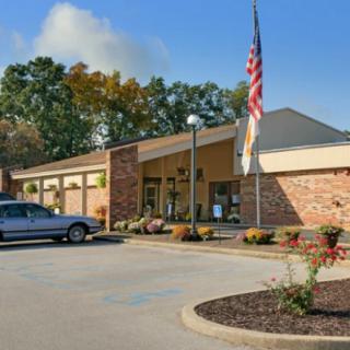 A one-story brick building with a parking lot and an American flag in front.