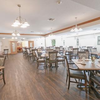 An empty dining area with neatly arranged tables and chairs under soft lighting.