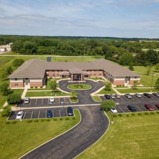 Aerial view of a large brick building with a surrounding parking lot and greenery.