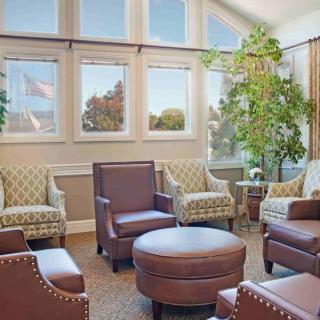 A cozy living room with comfortable armchairs, a coffee table, and large windows allowing natural light to fill the space.