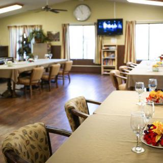A cozy dining room with set tables and a television on the wall.