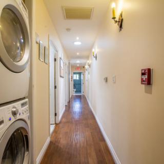A bright hallway with a stacked washer and dryer on the left.