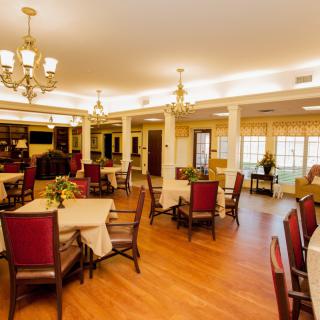A well-lit dining room with neatly arranged tables and chairs, featuring elegant chandeliers.
