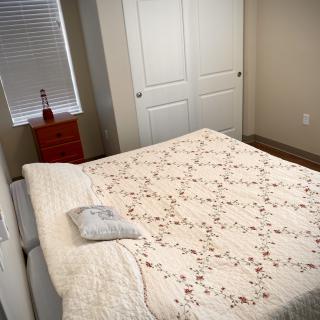 A cozy bedroom with a quilted bed, nightstand, and closed closet.