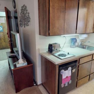 A compact kitchen setup featuring a toaster, stovetop, and television nearby.