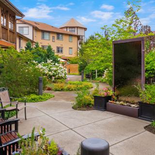 A serene courtyard garden with benches and lush greenery, surrounded by residential buildings.