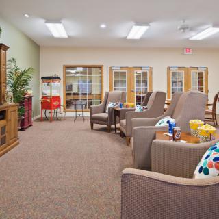 A cozy lounge area featuring comfortable armchairs, a popcorn machine, and an entertainment center.