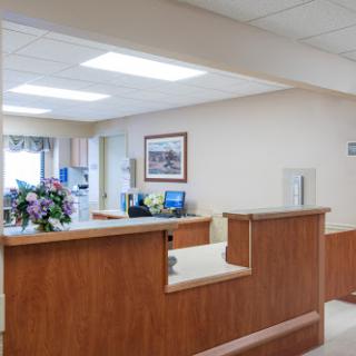 A modern reception area in a medical facility, featuring a welcoming desk and floral decorations.
