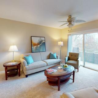 A cozy living room with comfortable seating, coffee table, and a sliding glass door leading to an outdoor balcony.