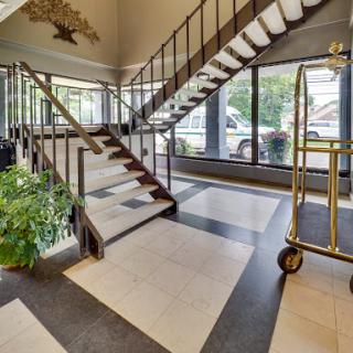 A spacious hotel lobby featuring a modern staircase and large glass windows.