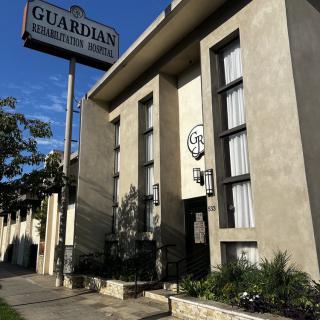 Exterior view of a building with a 'Guardian' sign and large windows.