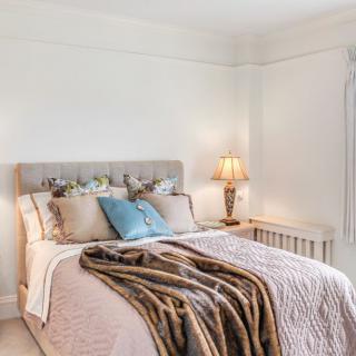 A cozy and elegantly decorated bedroom with a neatly made bed and a warm lamp.