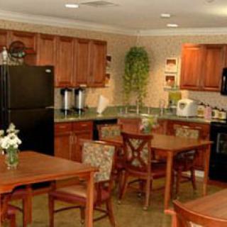 A cozy kitchen and dining area with wooden cabinets, a black refrigerator, and several dining tables.