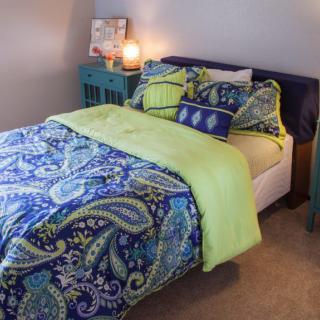 A cozy bedroom featuring a bed with colorful paisley-patterned bedding and vibrant accent pillows.
