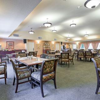 A spacious dining area with neatly arranged tables and chairs, warm lighting, and elegant decor.