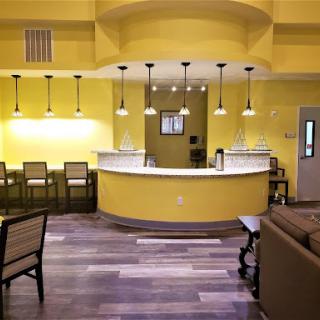 A modern reception area featuring bright yellow walls, stylish bar stools, and warm lighting.