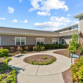 A well-maintained courtyard with landscaped gardens in front of a building under a blue sky.