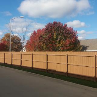 A serene autumn scene showcasing a wooden fence with vibrant trees and a clear blue sky.