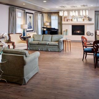 A spacious and elegantly decorated living room featuring comfortable seating, a fireplace, and a grand piano.