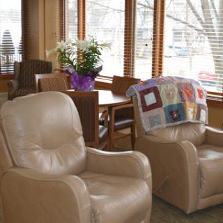 A cozy living room featuring comfortable recliners, a wooden table, and fresh flowers.