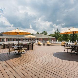 Spacious outdoor patio with tables and umbrellas under a cloudy sky.