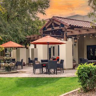 A serene outdoor dining area featuring comfortable seating and vibrant umbrellas, perfect for enjoying the sunset.