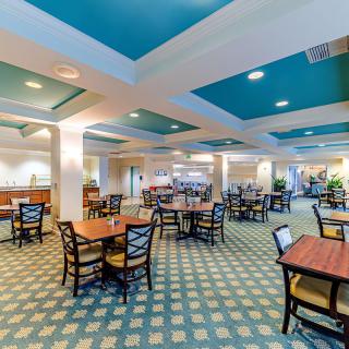 An elegantly designed dining room with multiple tables and chairs, featuring a stylish carpet and ceiling.