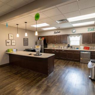 A modern kitchen with wooden floors, ample cabinetry, and overhead lighting.