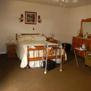 A vintage-style bedroom with a wooden bed and dresser, decorated with lamps and wall art.
