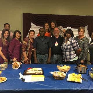 A cheerful group gathered for a celebration with food and dessert.