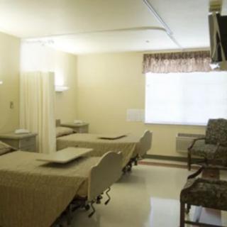A clean hospital room with two beds and chairs.
