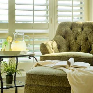 A cozy living room corner with a plush chair, side table, and sunlight streaming through the window.