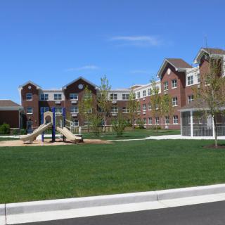 A residential building with a playground and green lawn on a sunny day.