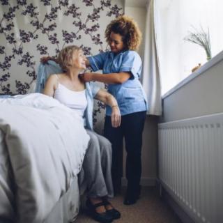 A caregiver assists an elderly woman in a home setting.