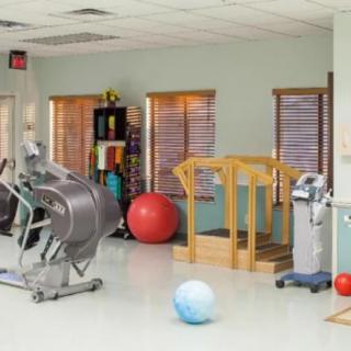A rehabilitation room equipped with various exercise equipment, including a treadmill and fitness balls.