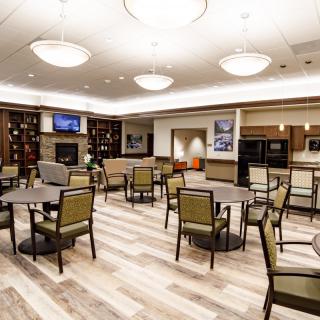 A modern dining area with neatly arranged tables and chairs, featuring elegant lighting and wooden flooring.