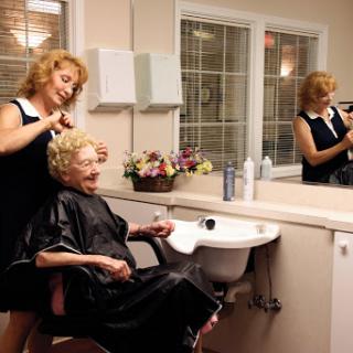 A hairstylist attending to an elderly woman in a cozy salon setting.