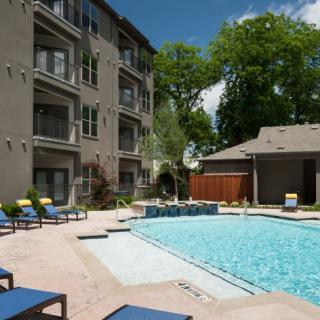 A tranquil apartment complex with a refreshing outdoor pool area on a sunny day.