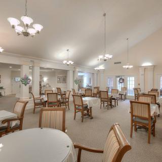A spacious dining room with neatly arranged tables and chairs under elegant chandeliers.