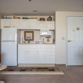A compact kitchen area in an apartment with white cabinets and appliances.