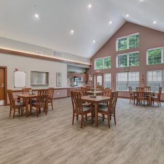 A spacious dining area with large windows and multiple round tables.