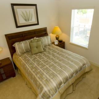 A cozy bedroom with a neatly made bed, nightstands with lamps, and a window providing natural light.