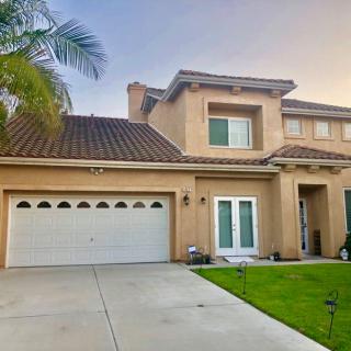 A two-story house with a garage, green lawn, and a palm tree at sunset.