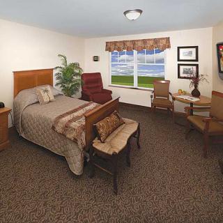 A well-furnished bedroom with a comfortable bed, chairs, and a window overlooking a scenic view.
