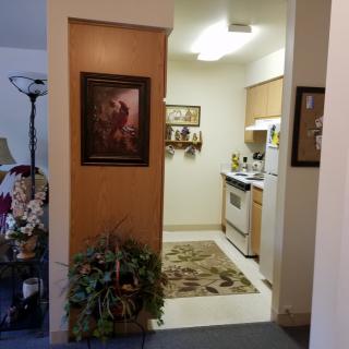 A cozy apartment kitchen with artwork and plants visible from the entrance.