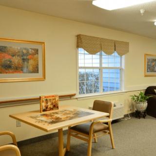 A cozy room with a table and chairs, decorated with wall art and a window view.