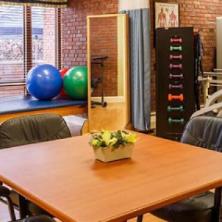 A well-equipped therapy room featuring exercise balls, weights, and a spacious table for rehabilitation activities.