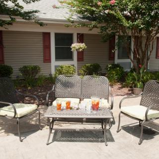 A cozy patio setup with a table and chairs, featuring refreshing drinks under the sun.