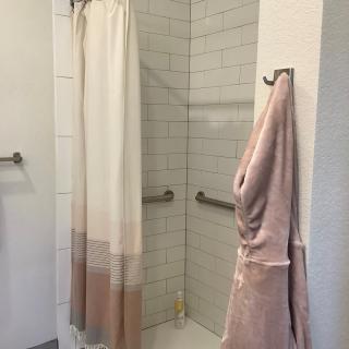 A clean and modern bathroom shower area with a tiled interior and hanging towel.